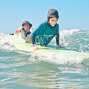 L'istruttore di surf sceglie l'onda giusta e dà una spinta alla tavola