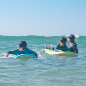 L'istruttore di surf è con i bambini nell'acqua bassa.