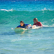 Istruttore di surf spinge un allievo nell'onda